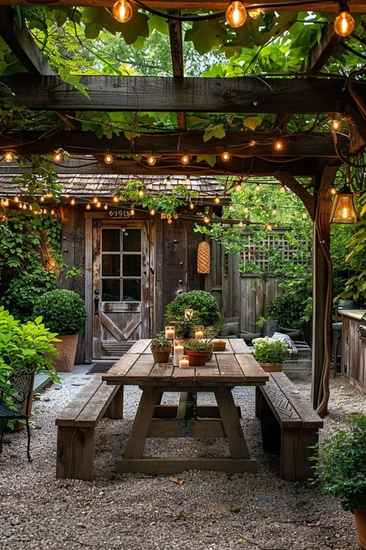 a wooden table sitting under a pergoline covered arbor with lights hanging from it