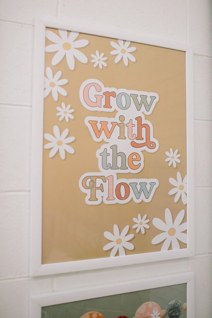 some flowers are hanging on the wall and there is a sign that says grow with the flow