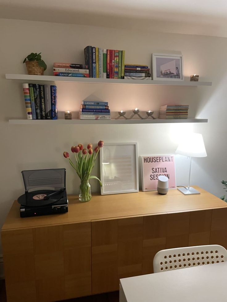 a room with a desk, bookshelf and pictures on the wall above it