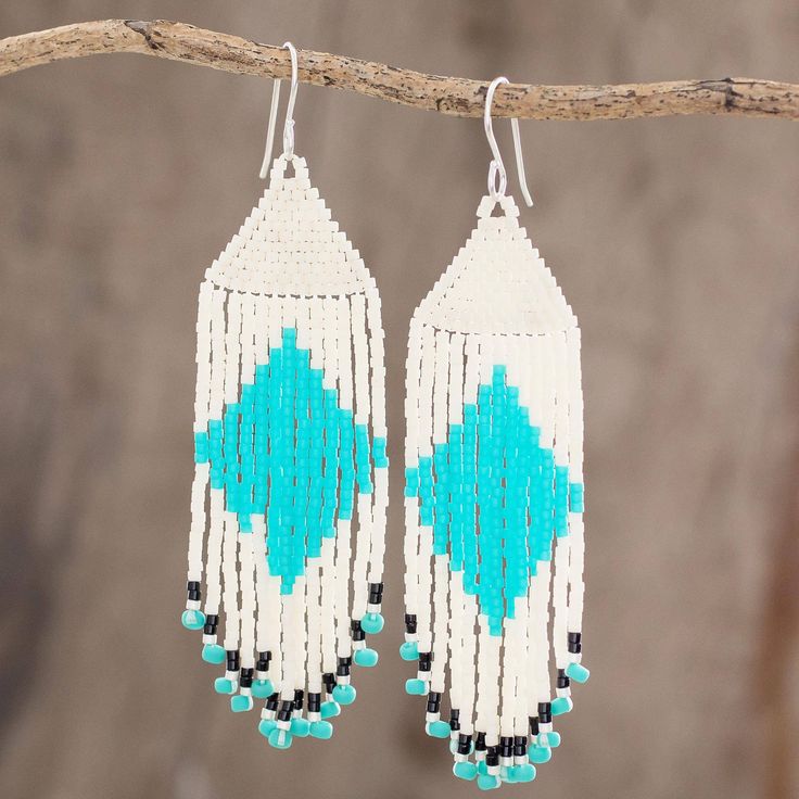 white and blue beaded earrings hanging from a tree branch