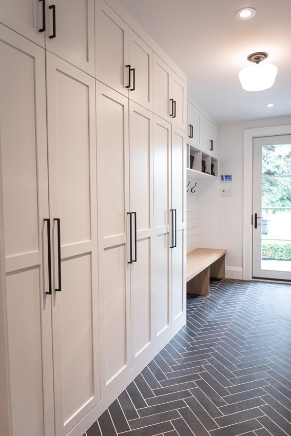 a kitchen with white cabinets and black tile flooring next to a large open door