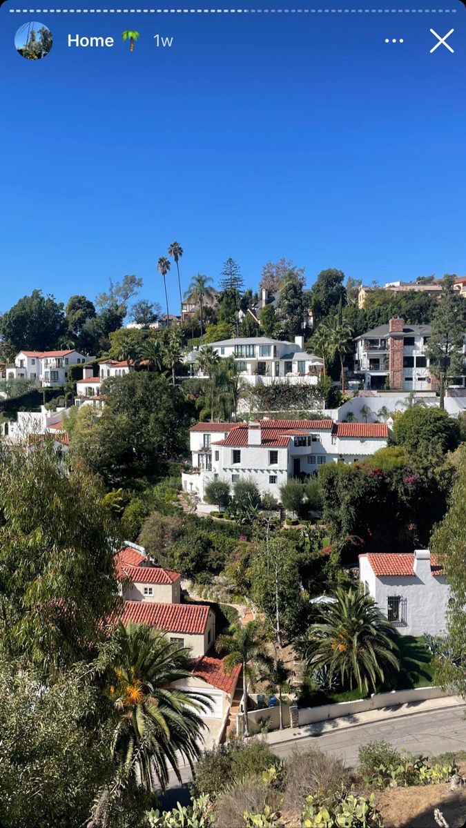 houses on a hillside with trees and blue sky