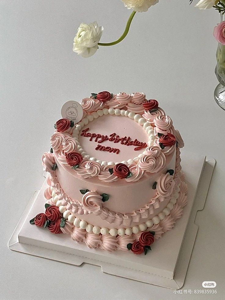 a pink birthday cake with roses on it