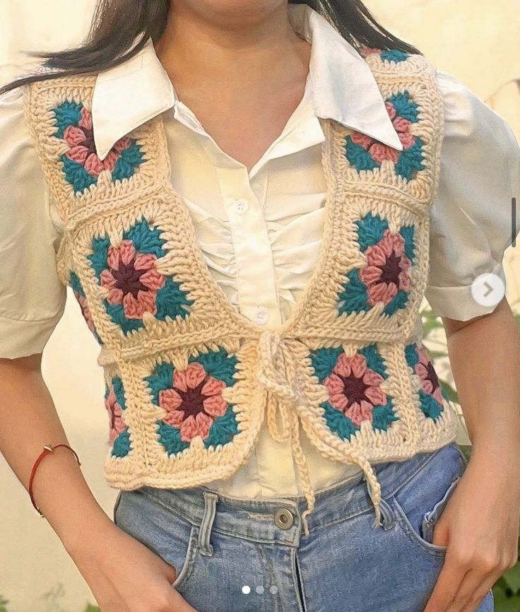 a woman is wearing a crocheted vest with flowers on it