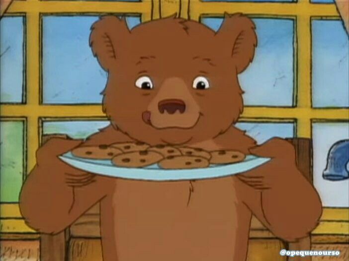 a brown bear holding a plate with cookies on it