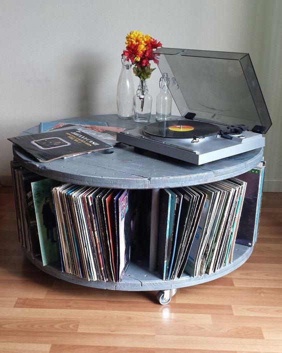 an old record player sits on top of a round table with cd's in it