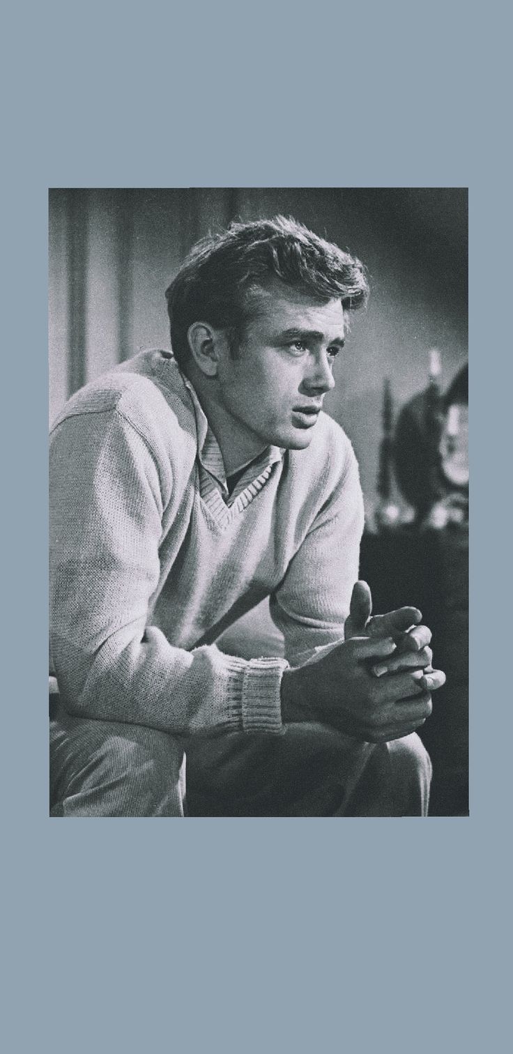 black and white photograph of man in sweater sitting on couch looking at something off camera