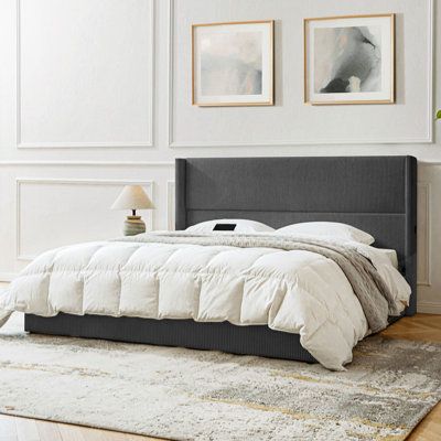 a large bed sitting on top of a wooden floor next to a white and gray wall