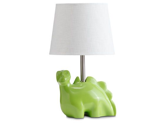 a green elephant lamp with a white shade on it's head and feet sitting next to a light