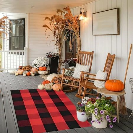 a porch decorated for fall with pumpkins and flowers