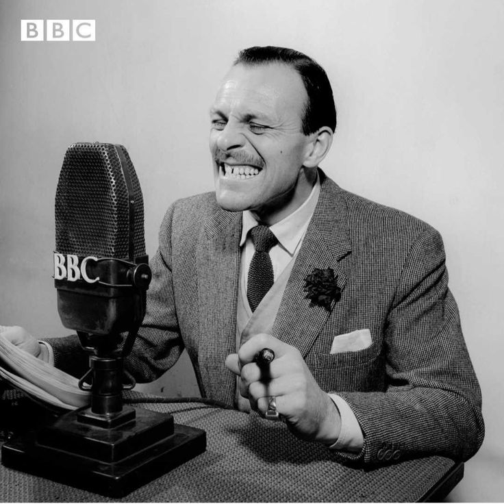 a man sitting in front of a microphone smiling