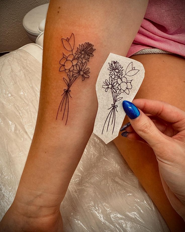 a woman's arm with flowers on it and a piece of paper in front of her