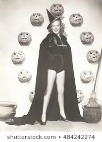 an old photo of a woman dressed as a witch in front of many pumpkins