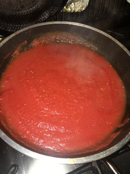 a pan filled with red sauce sitting on top of a stove