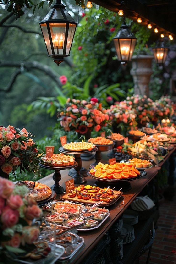 a long table filled with lots of food on top of it next to flowers and hanging lights