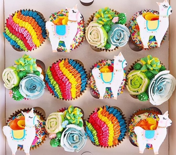 cupcakes decorated with colorful icing and flowers in a box on a table