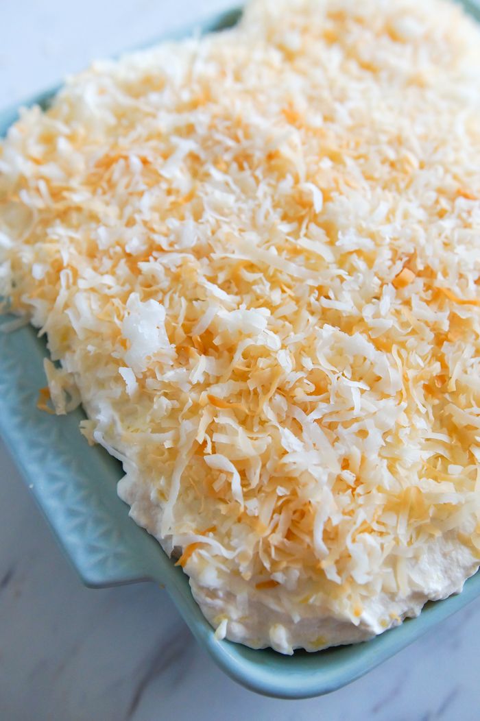 a close up of a cake on a plate with coconut toppings and frosting