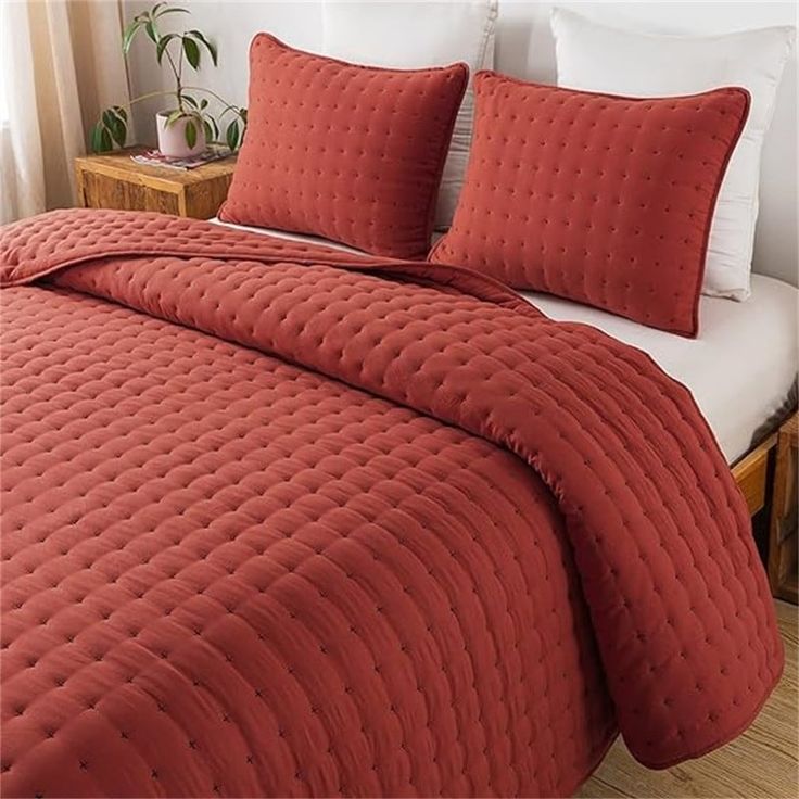 a bed with red bedspread and pillows on it