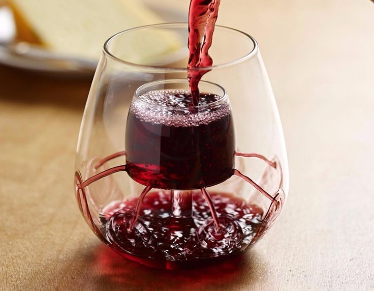 a glass filled with red wine being poured into it