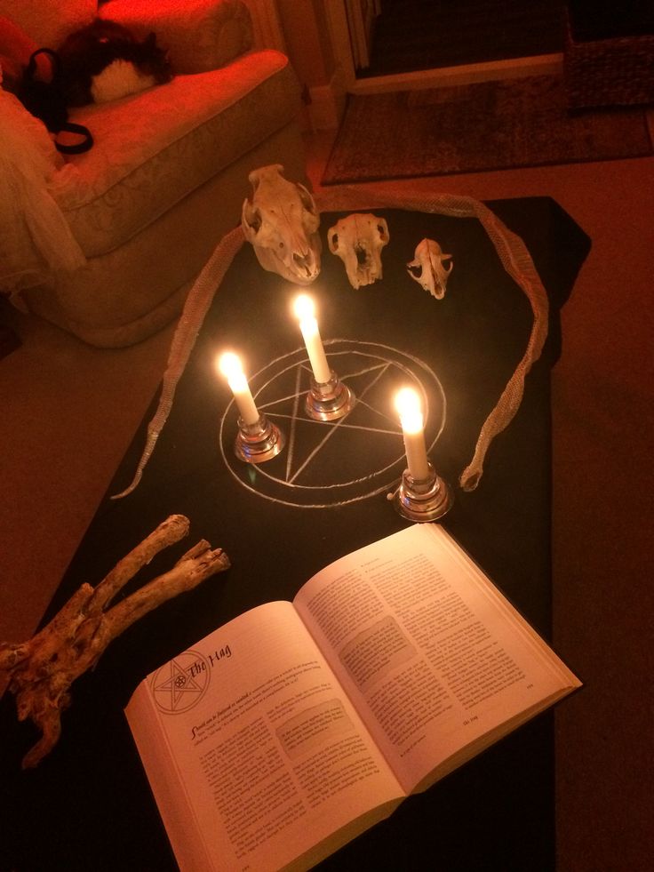 an open book sitting on top of a table next to two candles and some animal figurines