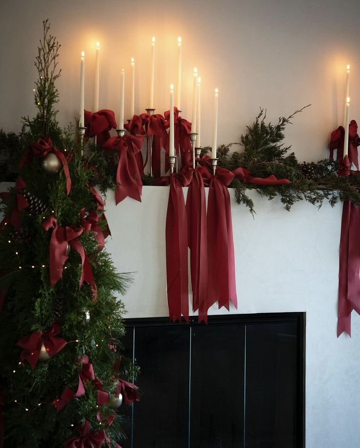 a fireplace decorated for christmas with candles and red bows on the mantel above it