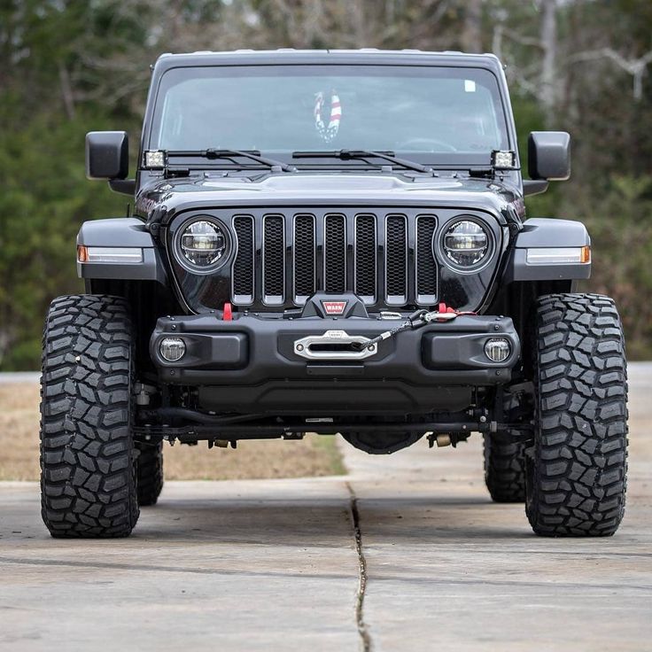 the front end of a black jeep parked in a parking lot