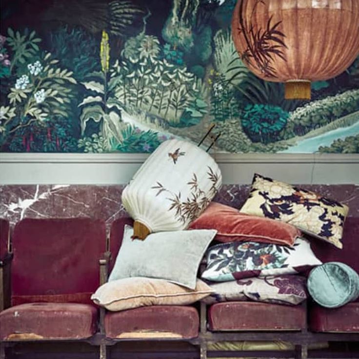 a bunch of pillows sitting on top of a couch in front of a wall mural