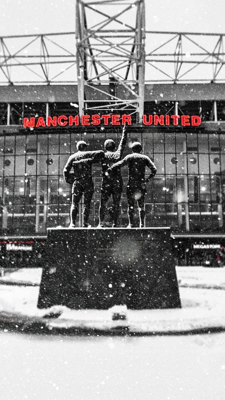 the statue is in front of manchester united's old emirates stadium with snow falling on it