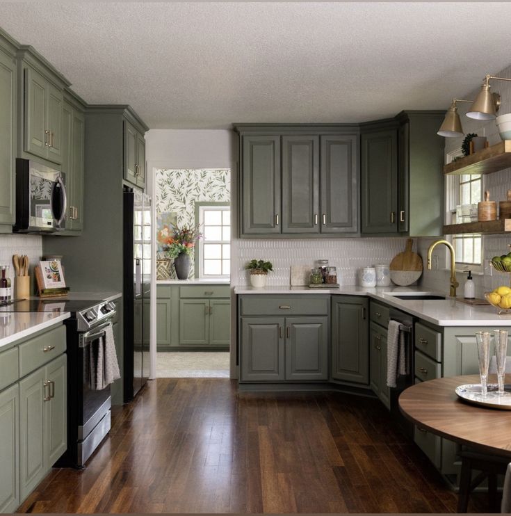 a kitchen filled with lots of green cabinets and counter top space next to a wooden floor