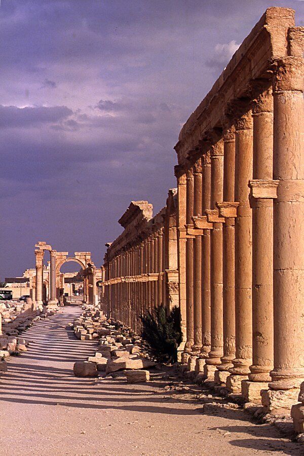 an empty street lined with ancient ruins and columns