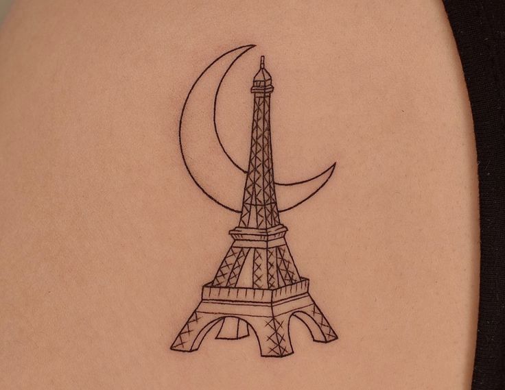 a small tattoo of the eiffel tower on the back of a woman's shoulder