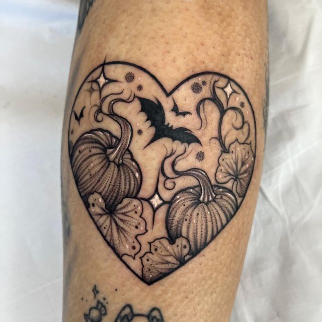 a heart shaped tattoo with pumpkins and bats