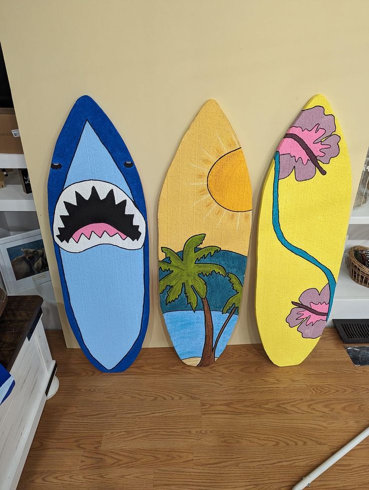 three surfboards painted to look like they are hanging on the wall next to each other