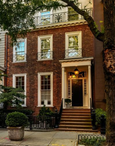 an old brick house with white windows and black wrought iron railings on the front door