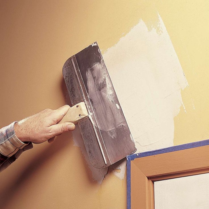 a man is painting the wall with a paint roller in his hand and he is holding a brush