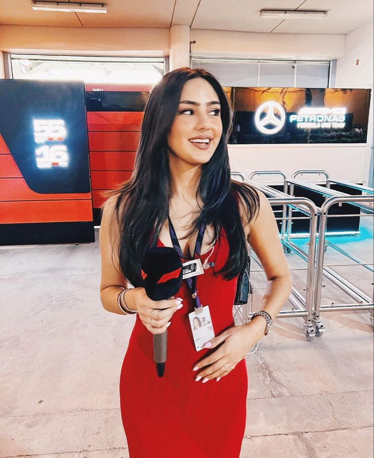 a woman in a red dress is holding a microphone and smiling at the camera,