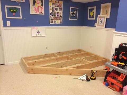 a room with blue walls and wood flooring in the process of being built into a bed frame