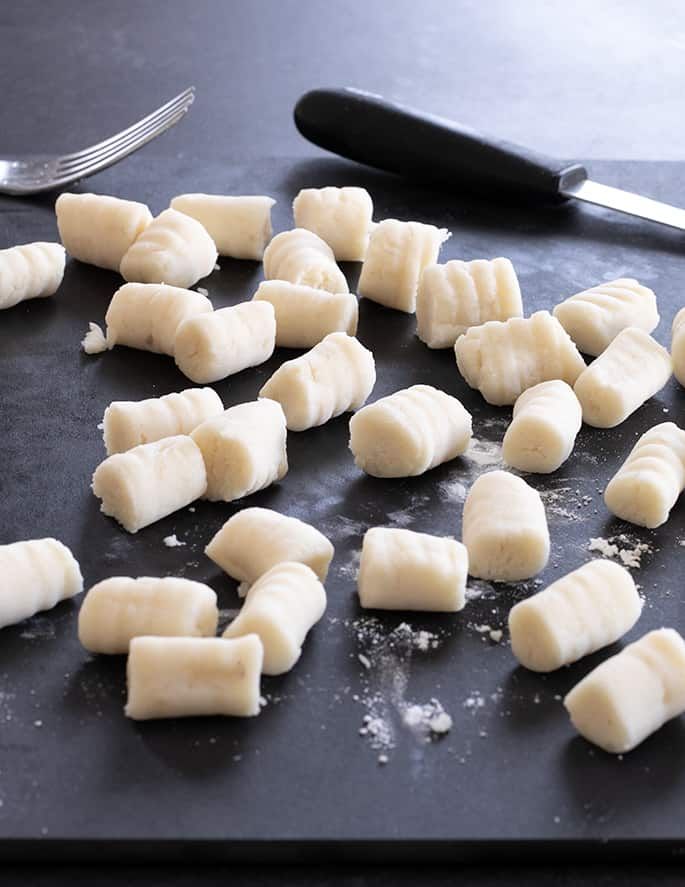 peeled bananas are on a cutting board with a knife and fork next to the chopped ones