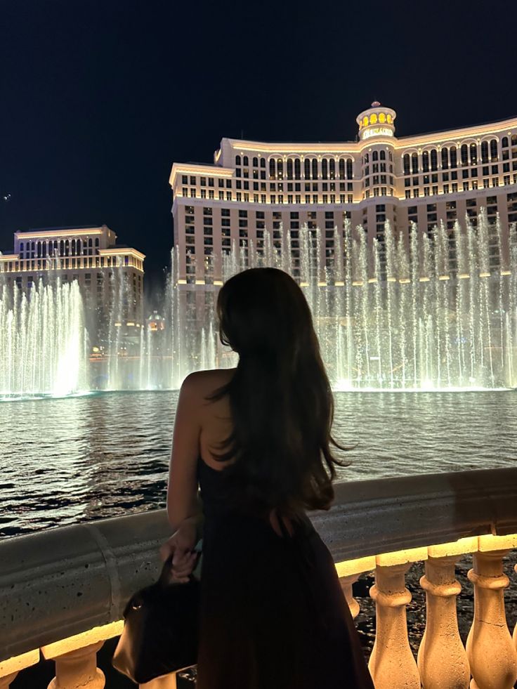 a woman looking at the fountains in front of the las vegas strip hotel and casino