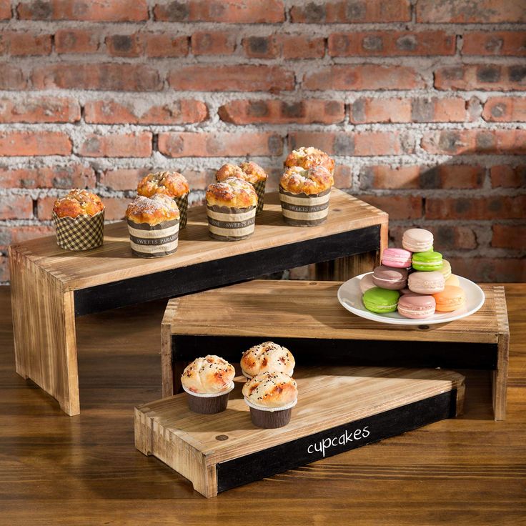 three wooden trays with cupcakes on them sitting on top of a table