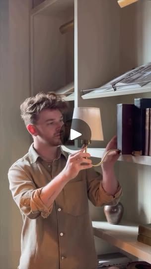 a man standing in front of a bookshelf holding a light up to his face