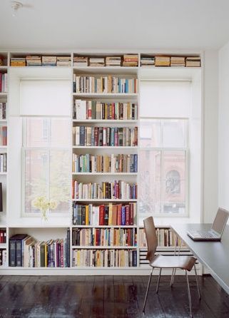 a room filled with lots of books and a laptop computer sitting on top of a desk