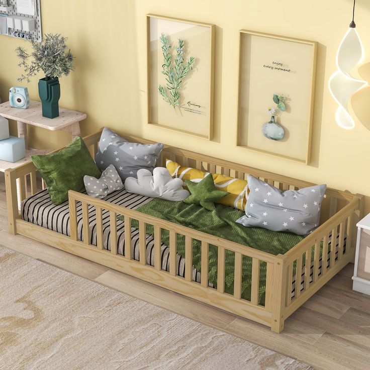 a baby's room with yellow walls and green pillows on the crib in front of two framed pictures