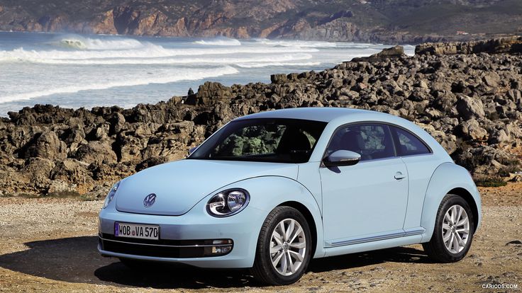 a light blue volkswagen beetle parked on the beach