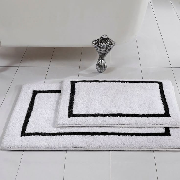 two bath mats sitting on top of a white tile floor