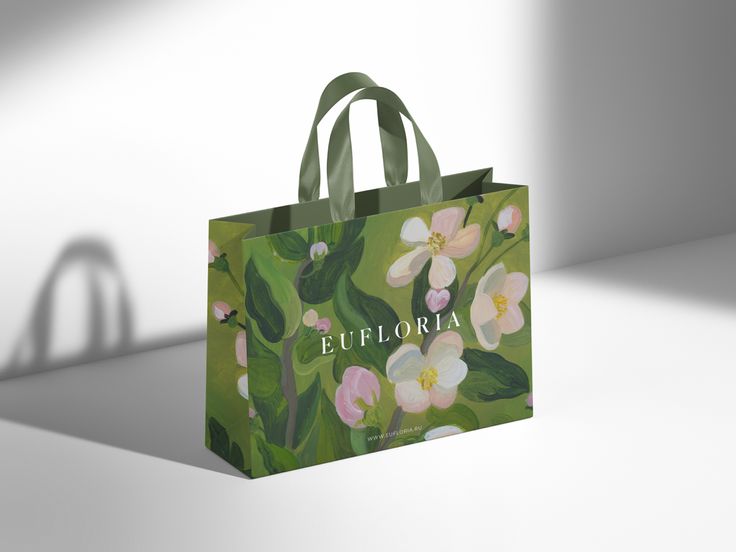 a shopping bag with an image of flowers painted on the front and side, sitting on a white surface