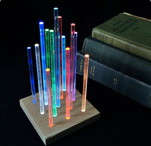 a group of multicolored candles sitting on top of a wooden stand next to a book