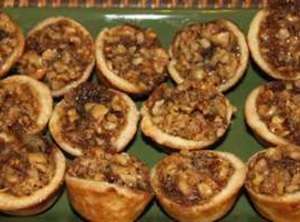 a green plate topped with mini pies covered in nuts