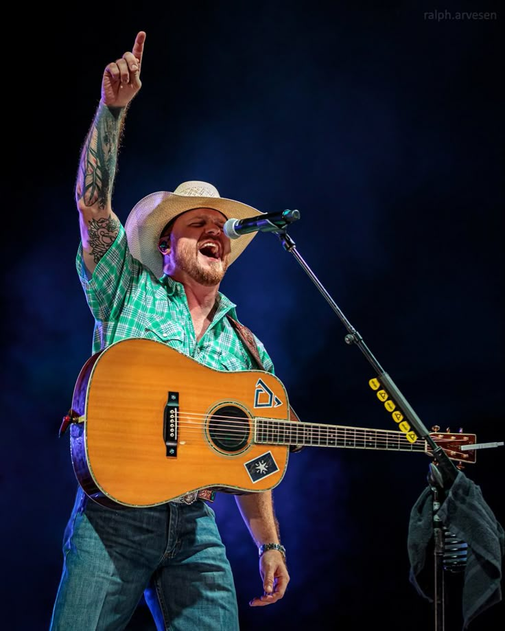 a man with a guitar and microphone on stage