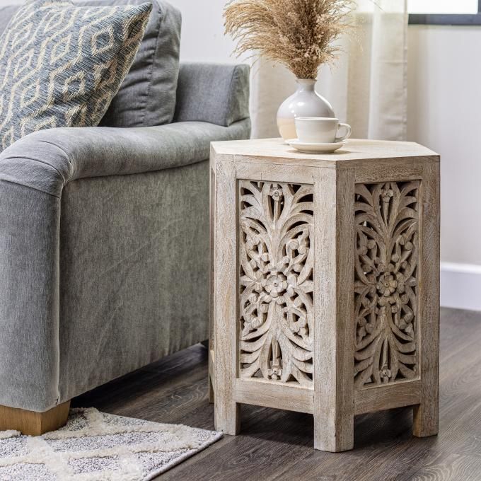 a white vase sitting on top of a wooden table next to a gray couch in a living room